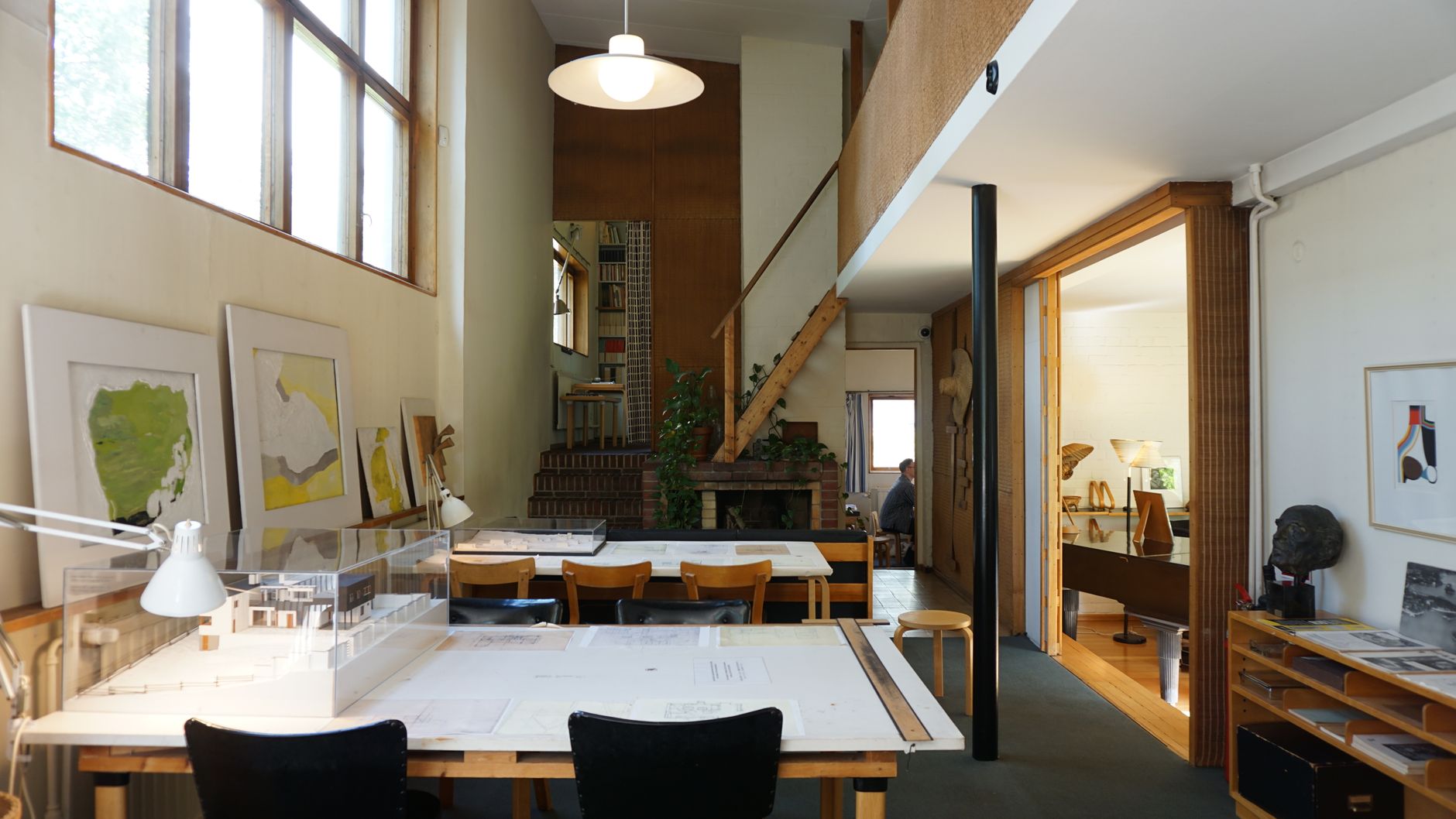 Maqueta arquitectónica en madera sobre una mesa de trabajo con planos